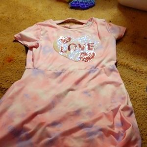 A pink dress that says love and around it is a white sparkley heart